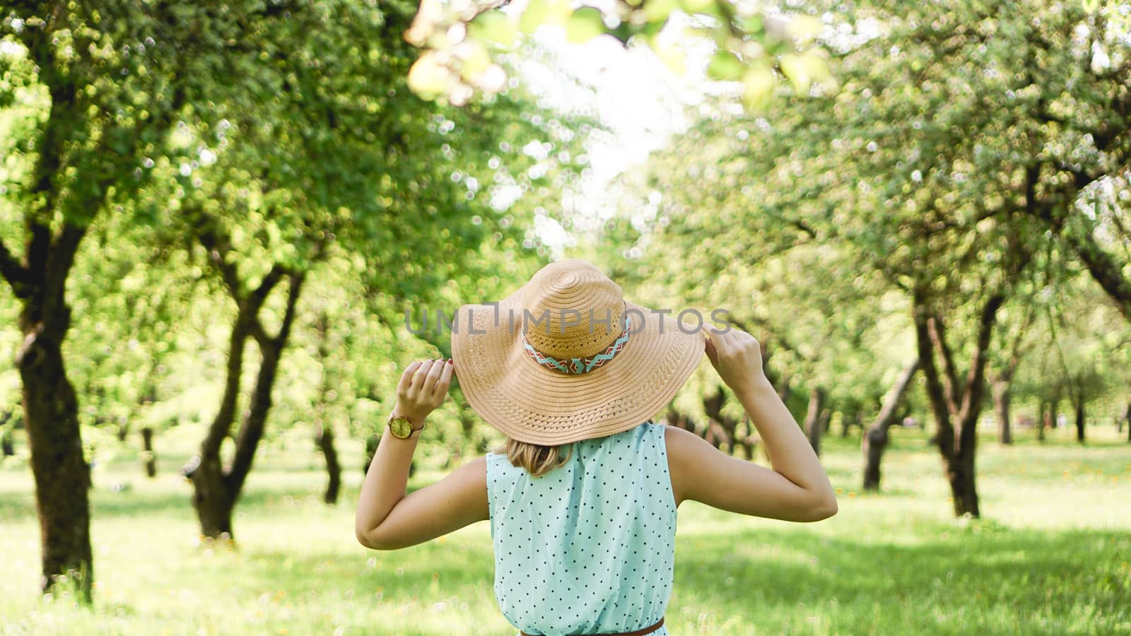 Happy young woman in straw hat in sunny garden