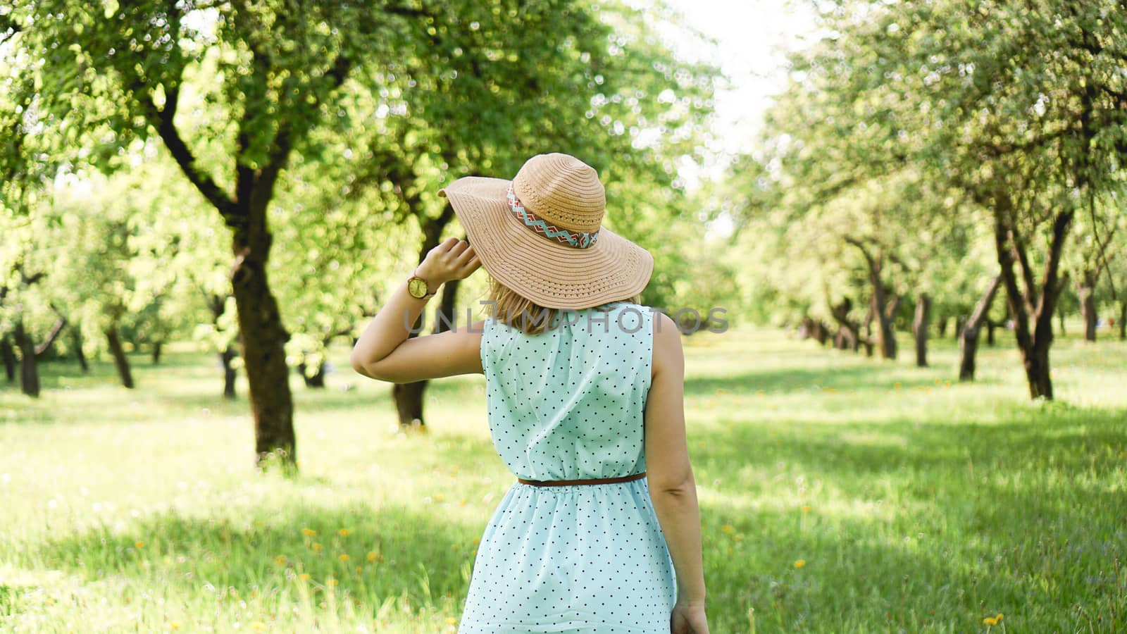 Happy young woman in straw hat in sunny garden