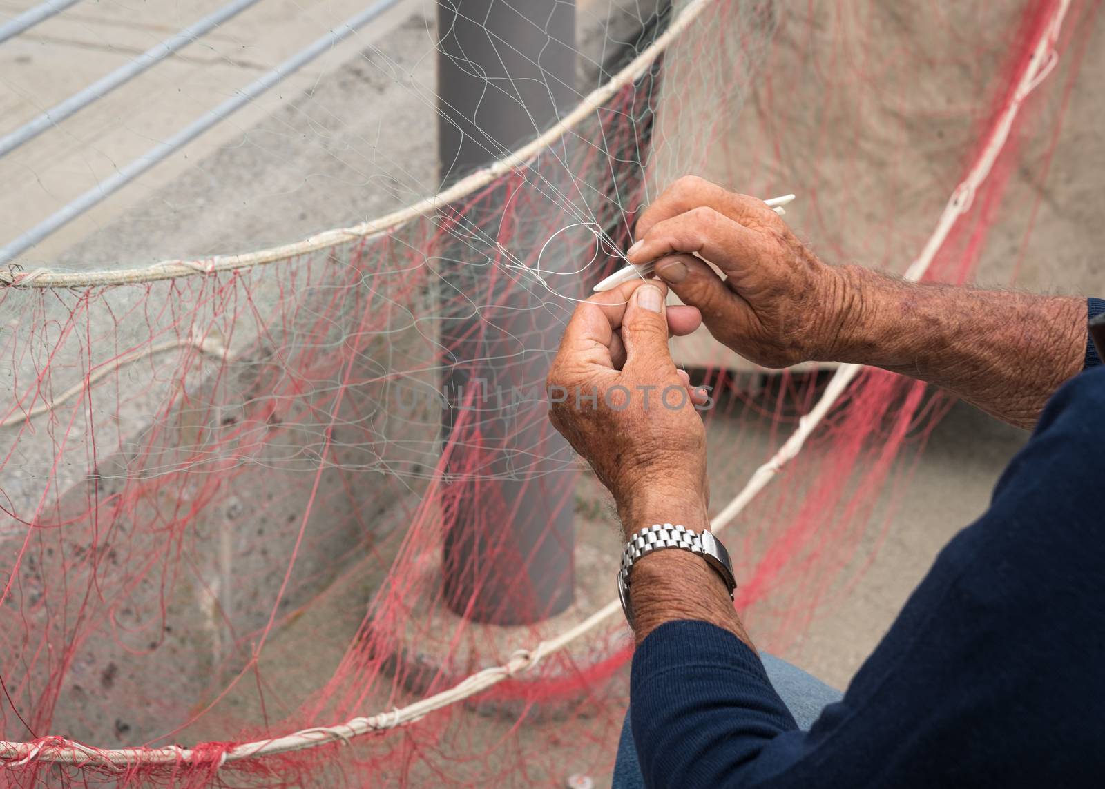 Old fisherman reparing fishing net.