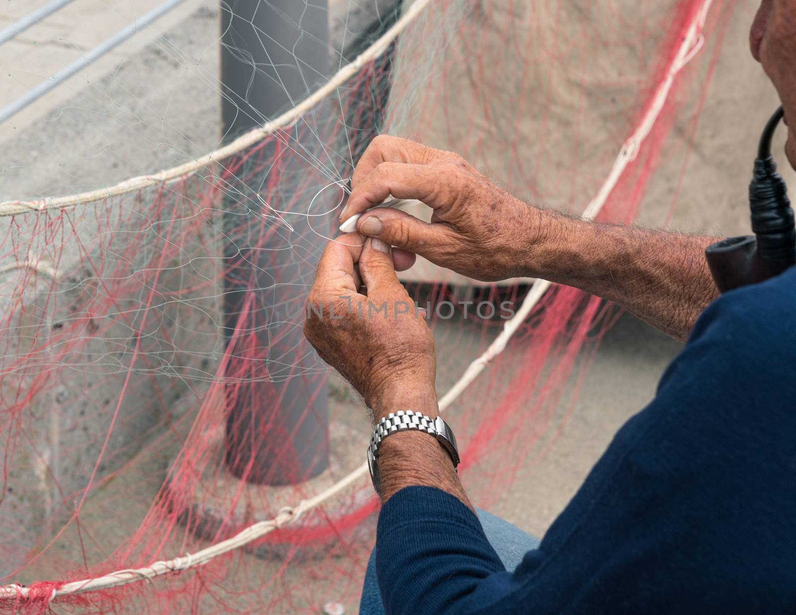 Senior fisherman reparing fishing net by Robertobinetti70