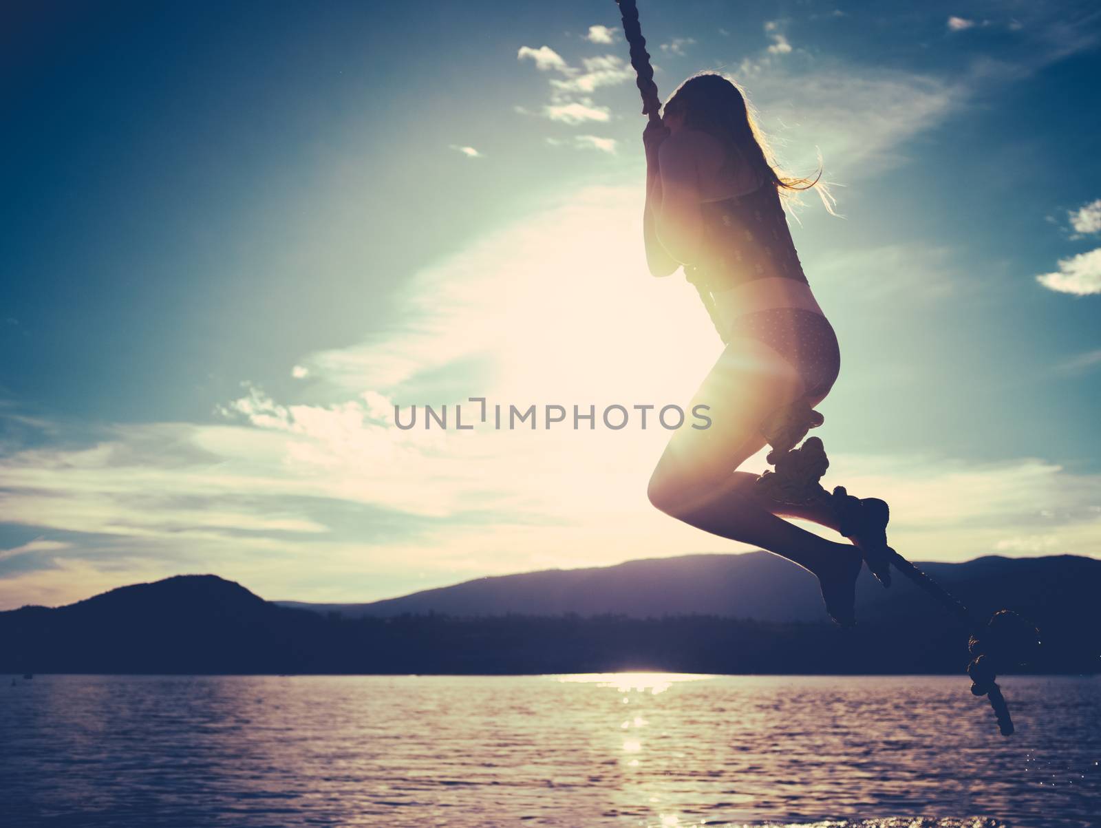 Retro Style Summertime Image Of A Girl Swinging Into A Lake At Sunset With Copy Space