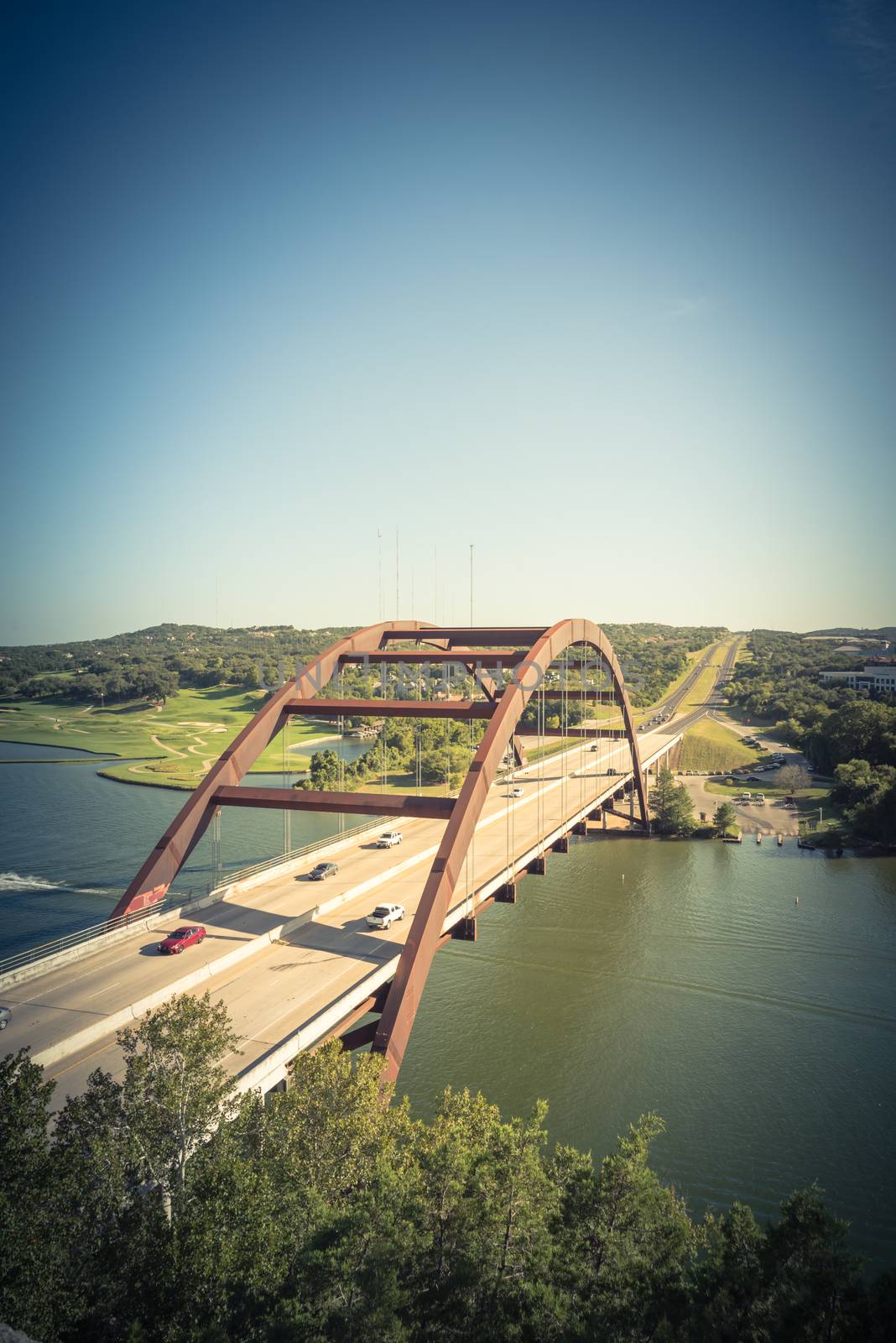Vintage tone elevated view of Pennybacker Bridge or 360 Bridge with car traffic at daytime. A landmark in Austin, Texas, USA. Top of Town Lake, Colorado River and Hill Country green landscape