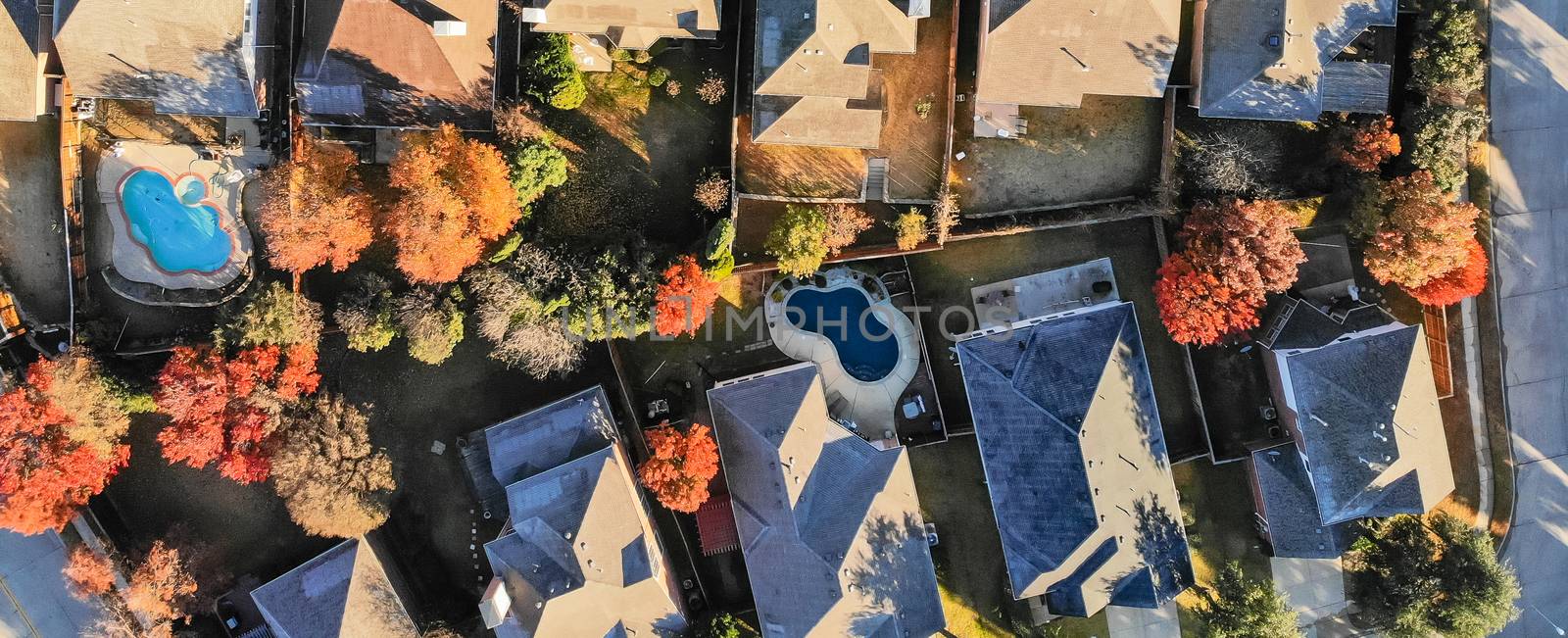 Panorama straight looking aerial view of typical houses colorful fall color near Dallas, Texas. Fly-over single-family home with large garden, swimming pool. Light snow on roof in cold early morning