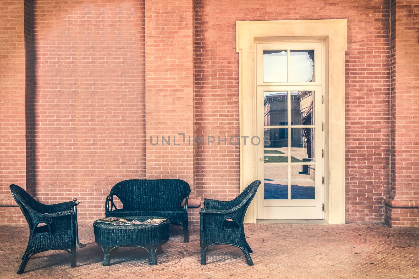 waiting room outside modern elegant with table magazines wooden armchairs stone walls and white door .