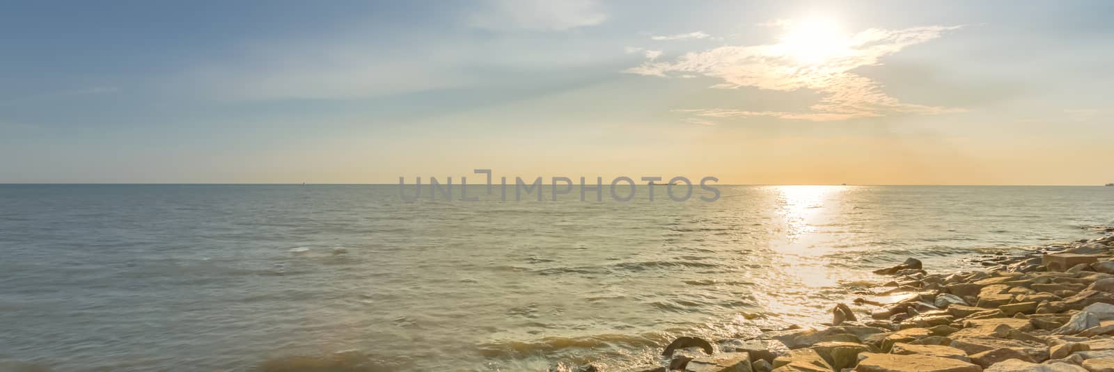 Panorama view beautiful sunset over horizontal at Melaka, Malaysia. Long man made rock sand break, surf break wall along the shore