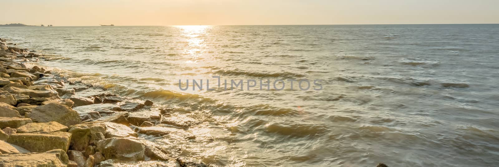 Panorama view beautiful sunset over horizontal at Melaka, Malaysia. Long man made rock sand break, surf break wall along the shore