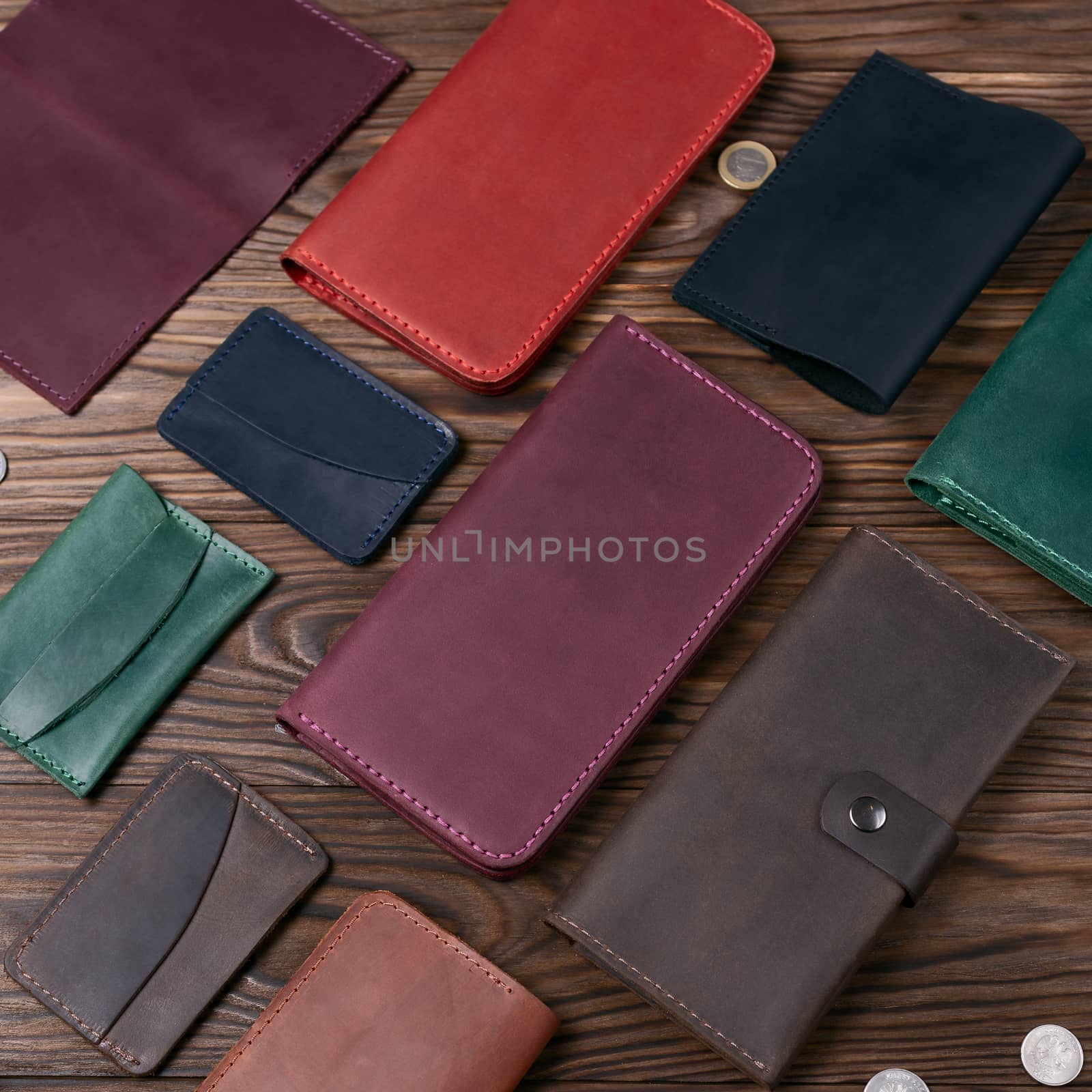 Purple color handmade leather porte-monnaie surrounded by other leather accessories on wooden textured background.  Side view. Stock photo of luxury accessories.