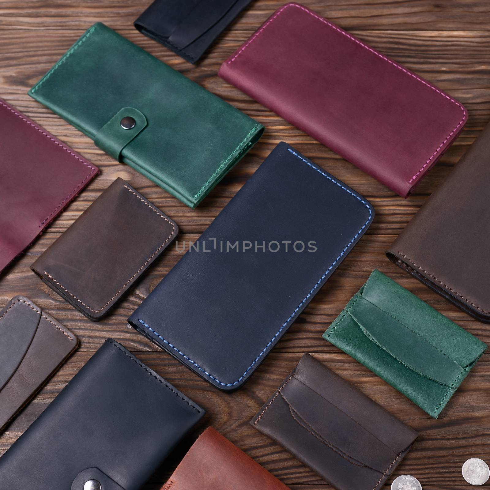 Blue color handmade leather porte-monnaie surrounded by other leather accessories on wooden textured background. Side view. Stock photo of luxury accessories.