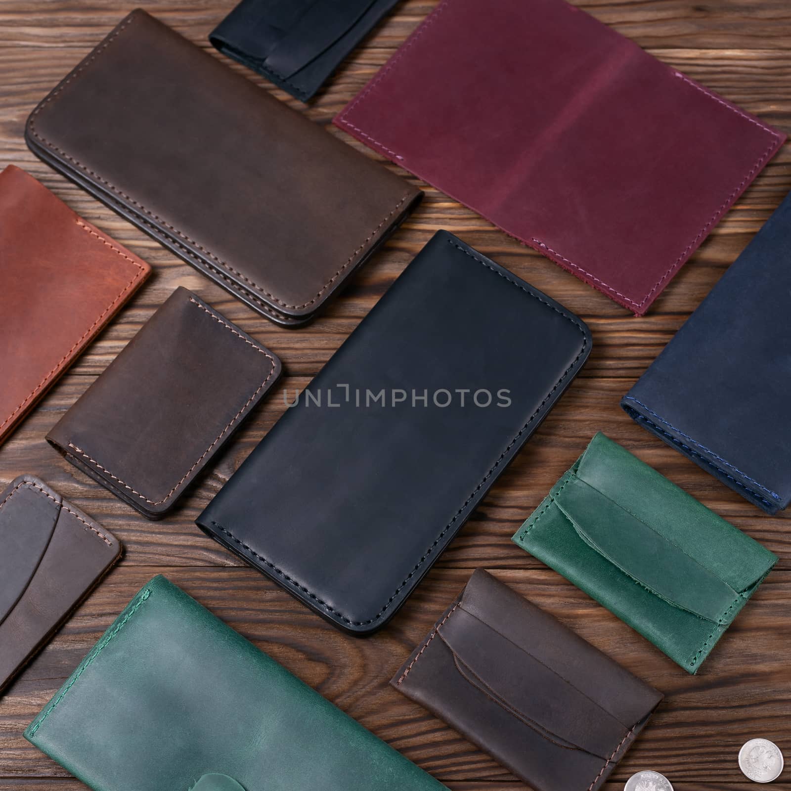 Black color handmade leather porte-monnaie surrounded by other leather accessories on wooden textured background. Side view. Stock photo of luxury accessories. by alexsdriver