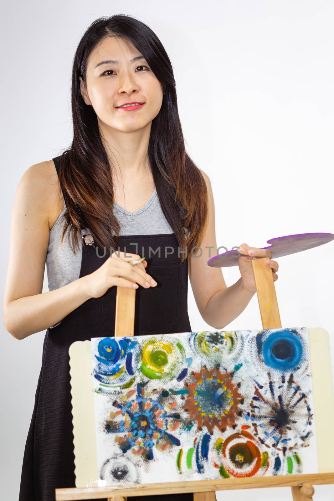 Artist standing behind painting holding palette and brush