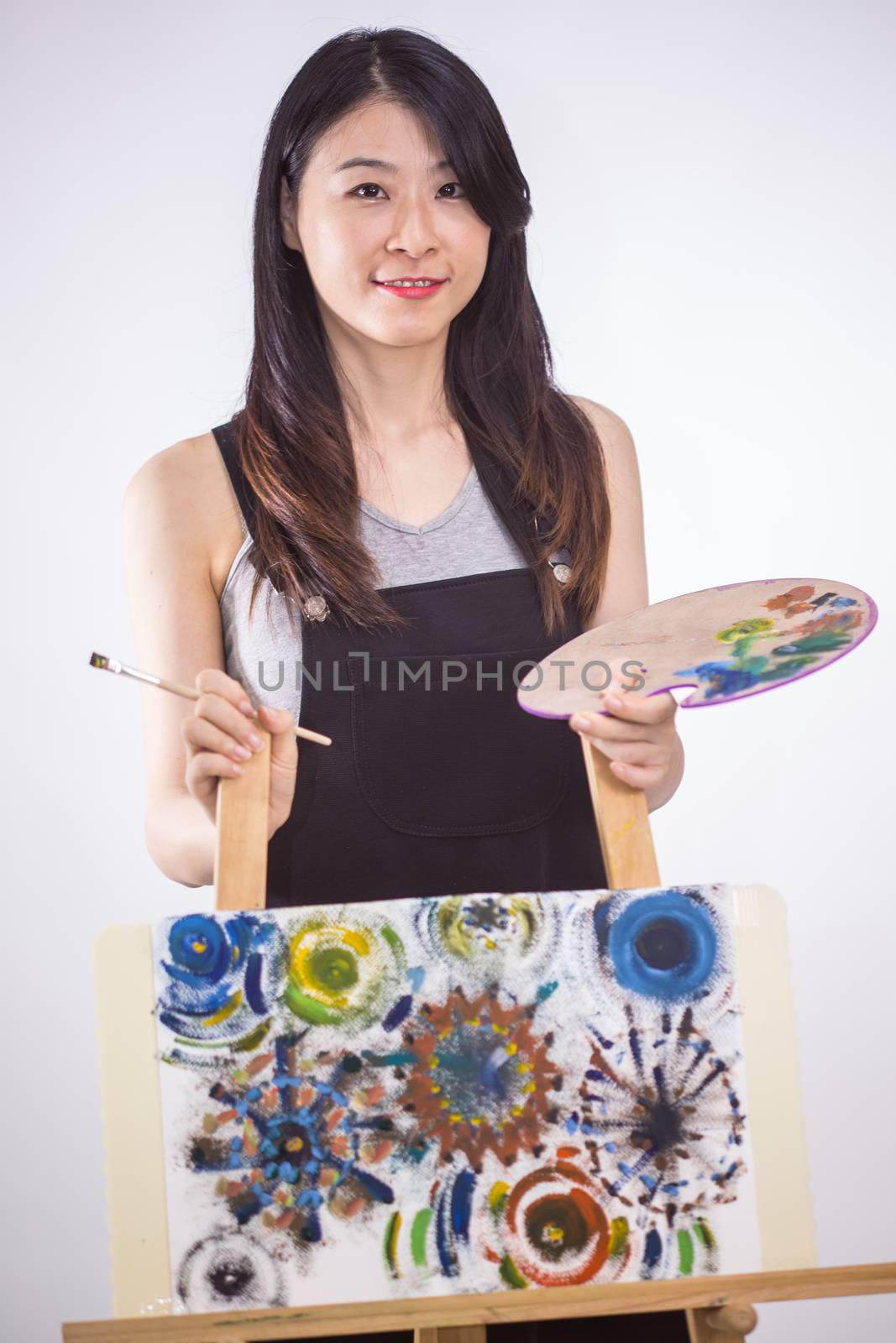 Artist standing behind painting holding palette and brush