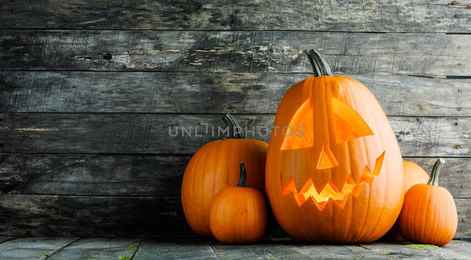 Halloween glowing pumpkin head jack o lantern on gray wooden background