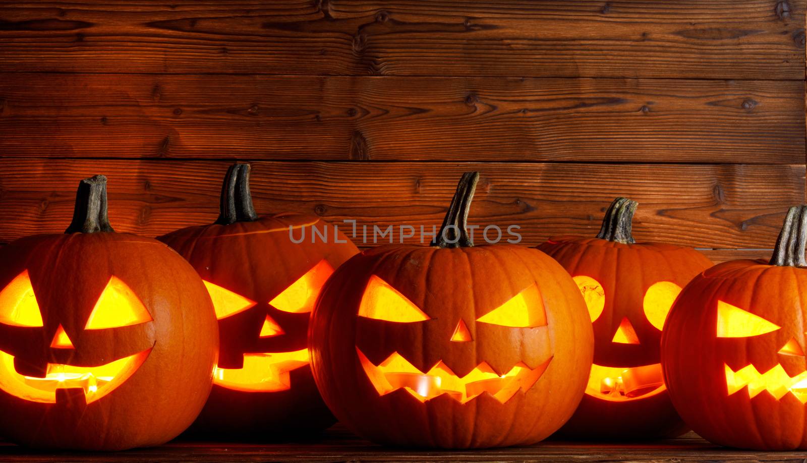 Glowing Halloween pumpkins head jack o lantern on wooden background