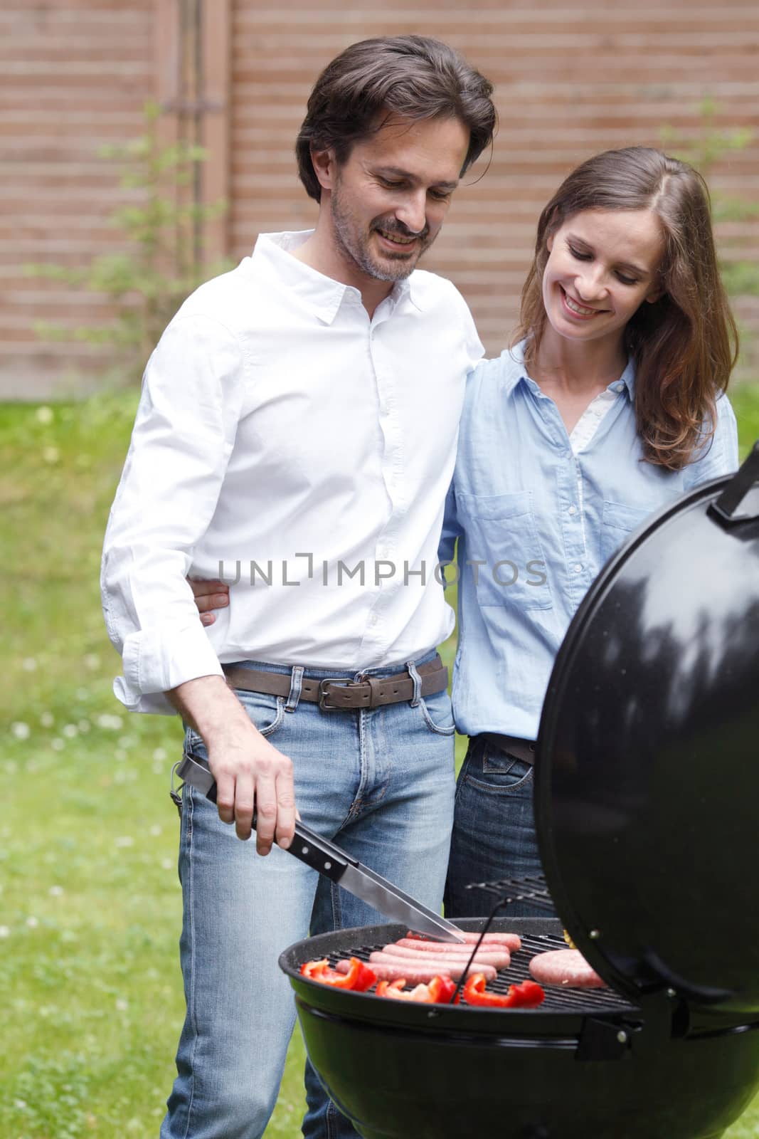 Happy couple cooking food on barbecue grill outdoors