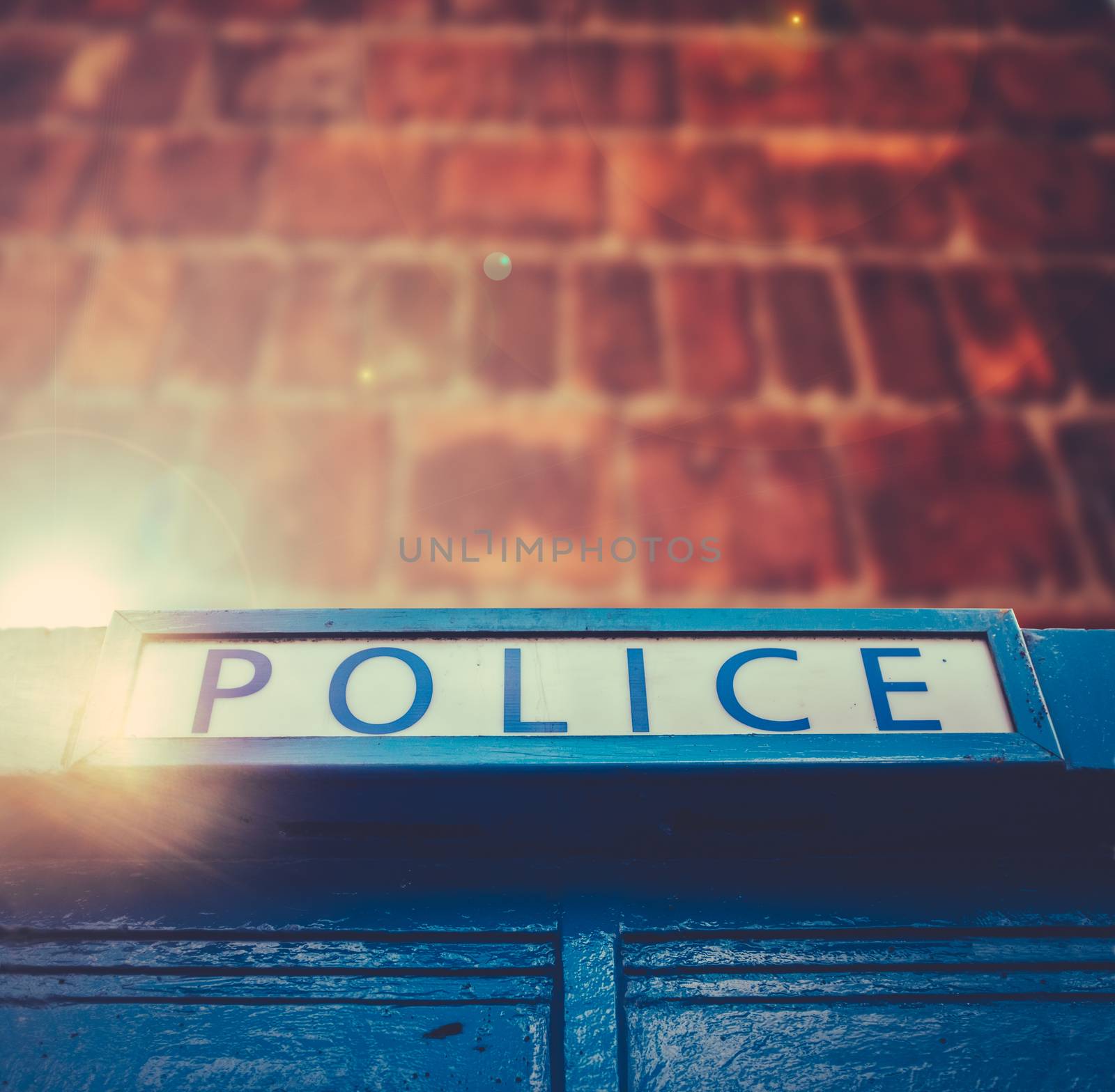 British Police Box With Lens Flare Against A Red Brick Wall With Copy Space