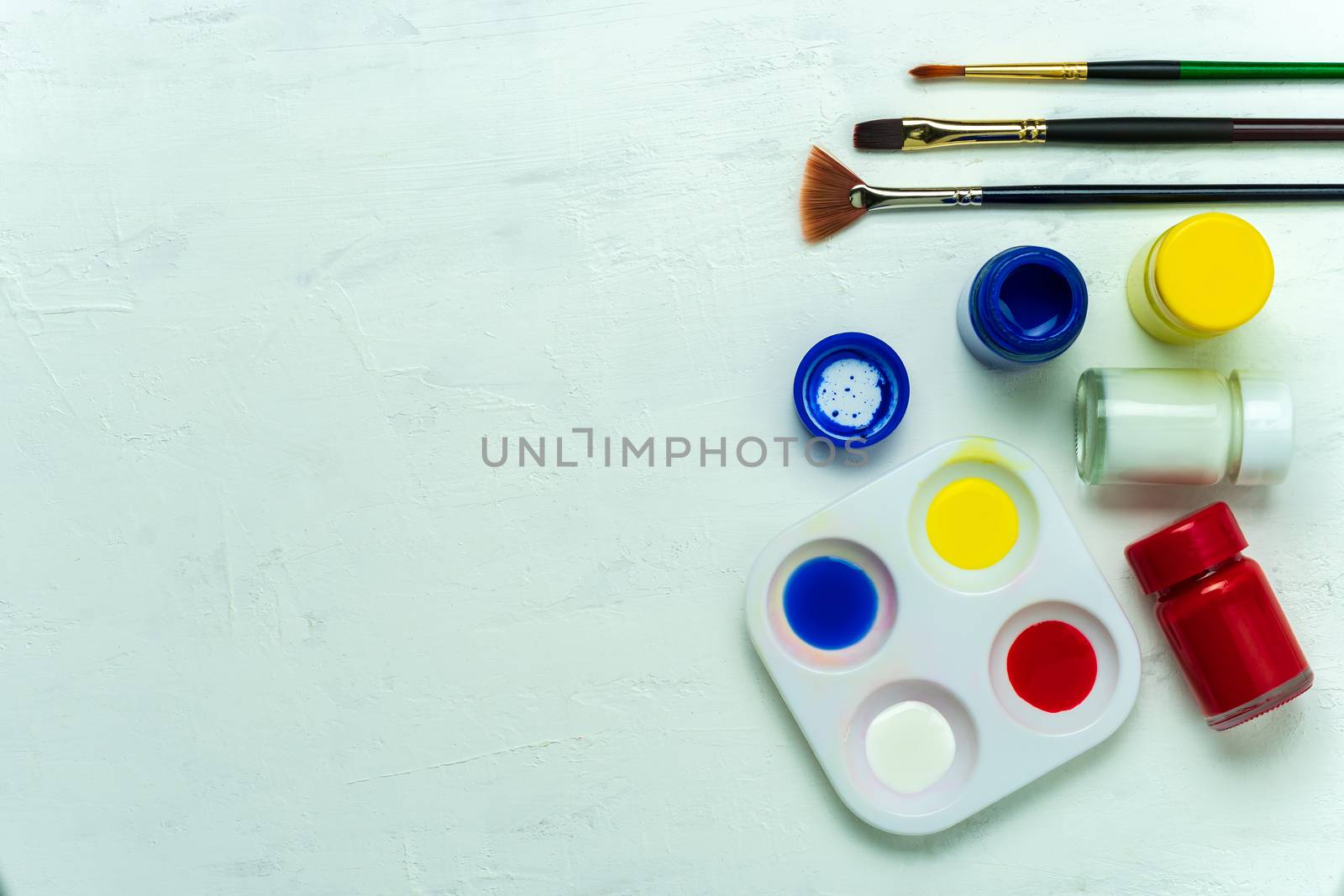 Palette and watercolor with paint brush on white background. Top view and copy space.