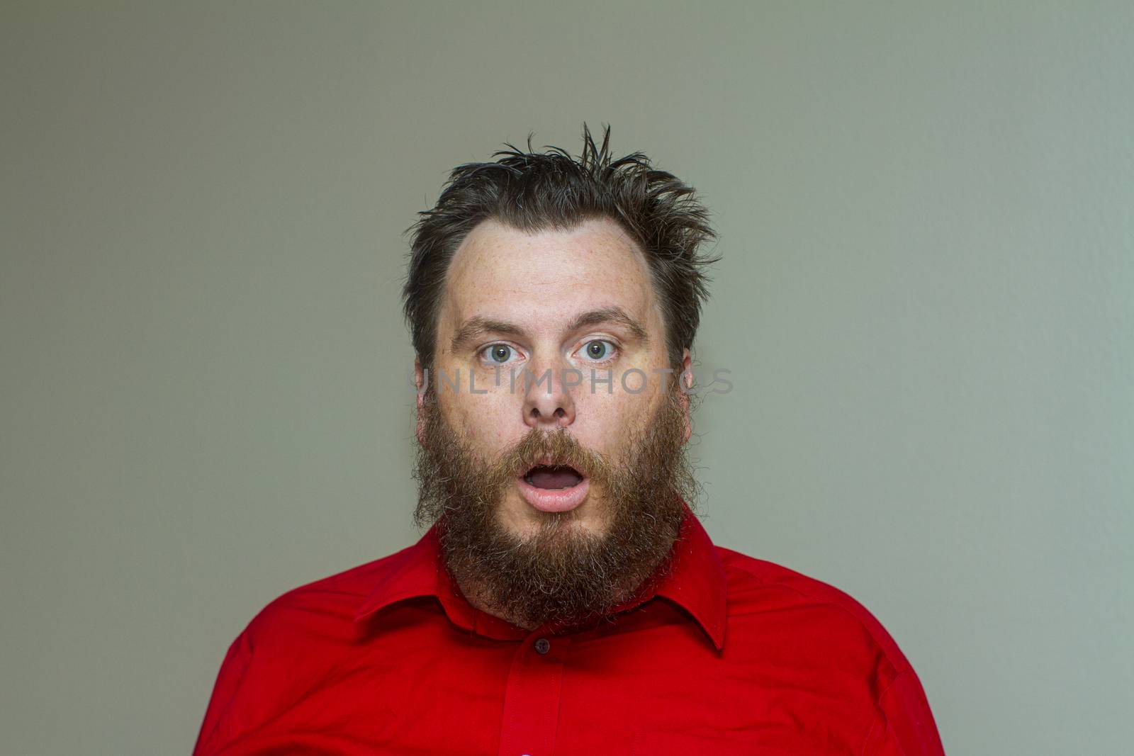 Man holding his mouth barely open like he is either very tired or stoned while wearing a business shirt