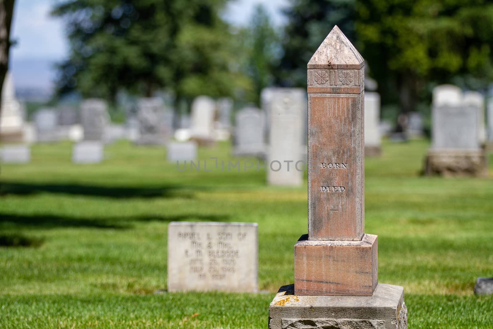 Large pillar in a cemetery with the born and died words still on there.