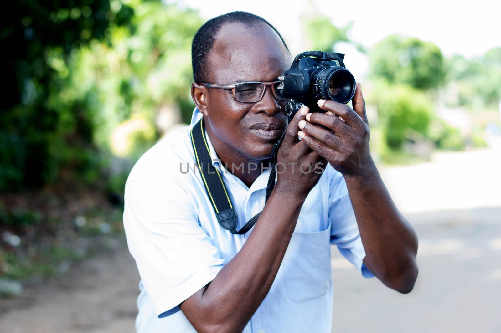 people, photography, entertainment and lifestyle - happy young man holding a digital camera and taking pictures on the street of the campaign