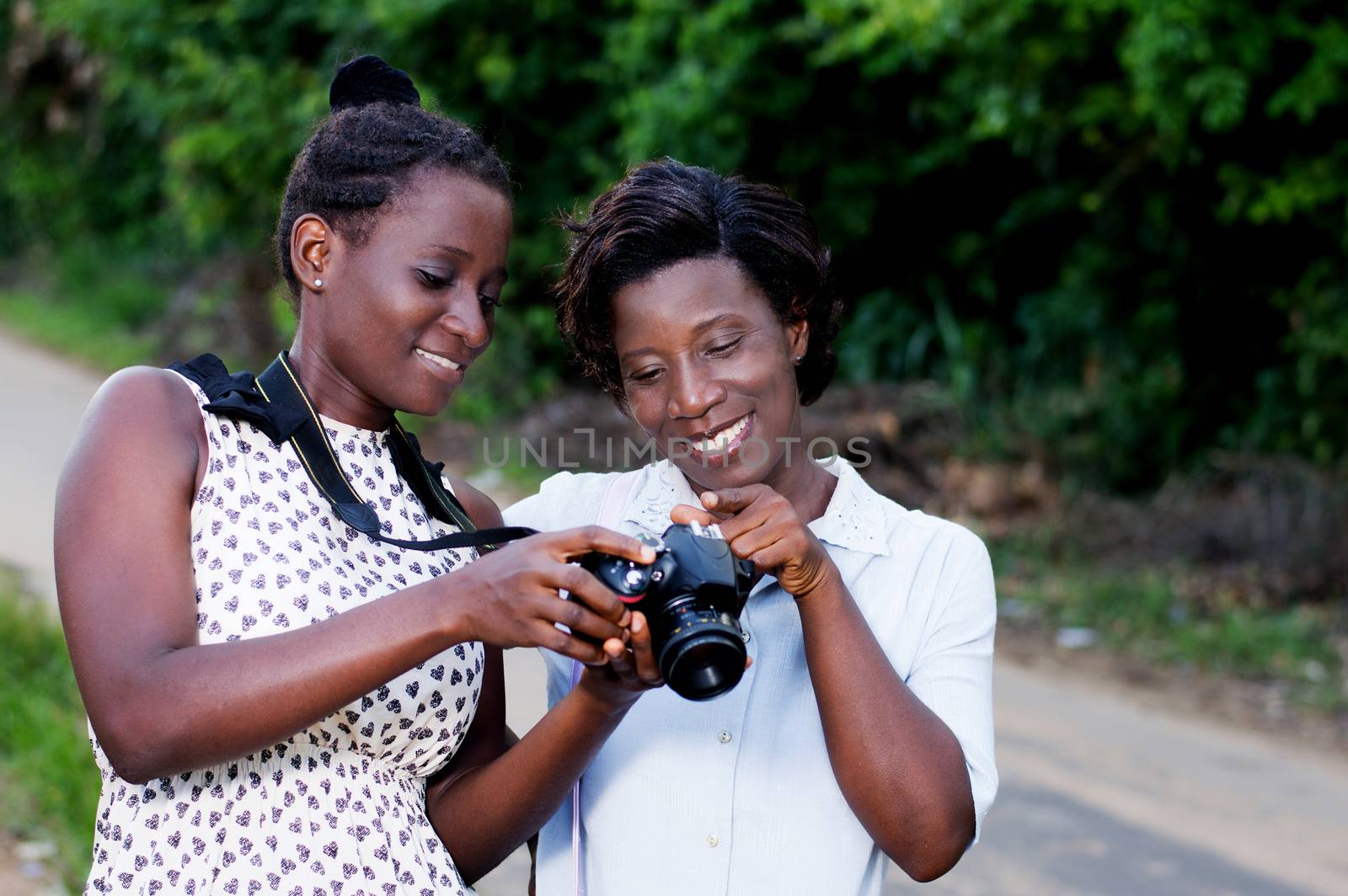 Young women happy, watching pictures on the screen of their came by vystek