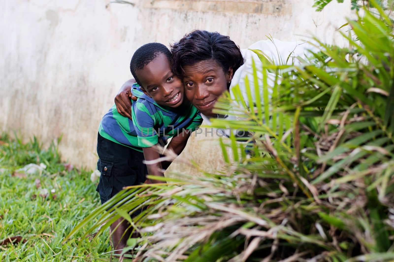young woman hidden behind a flower with her child and spy on someone.
