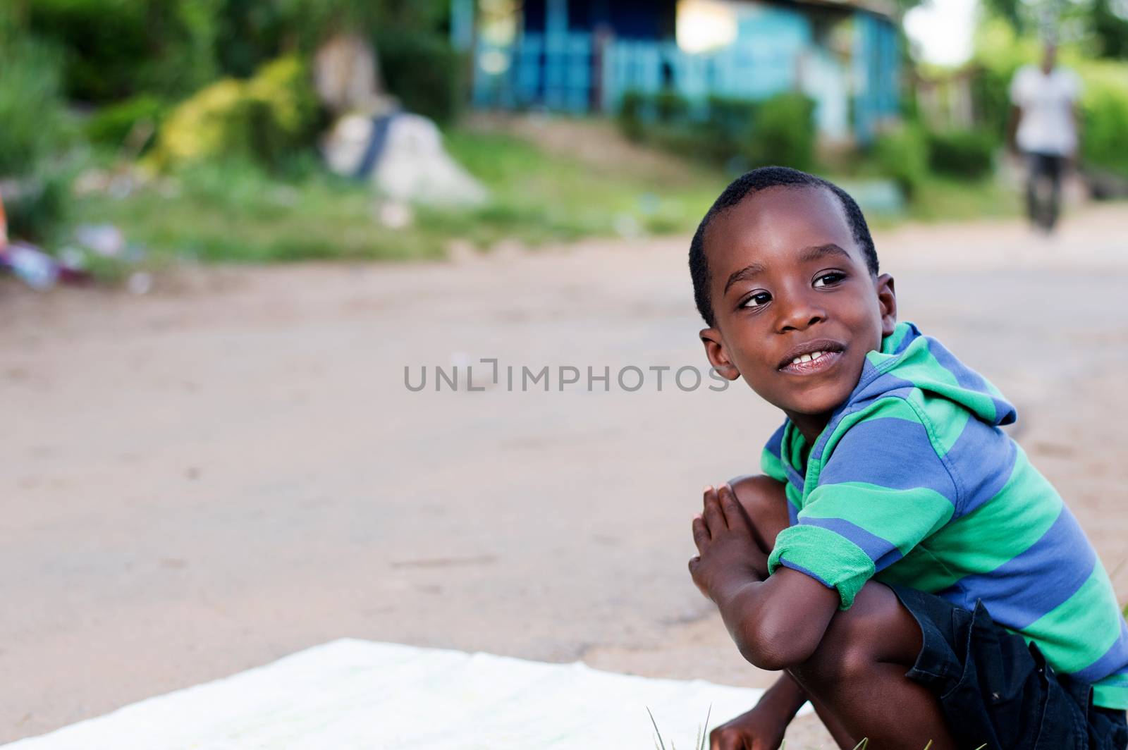 cheerful child crouching beside the road looking at the camera.