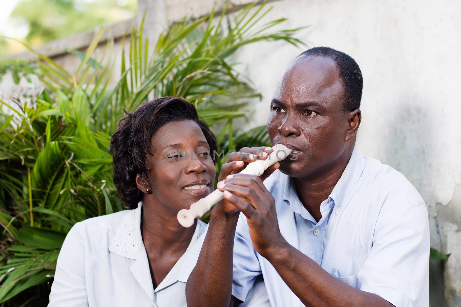 adult woman watching her husband play the flute, smiling.