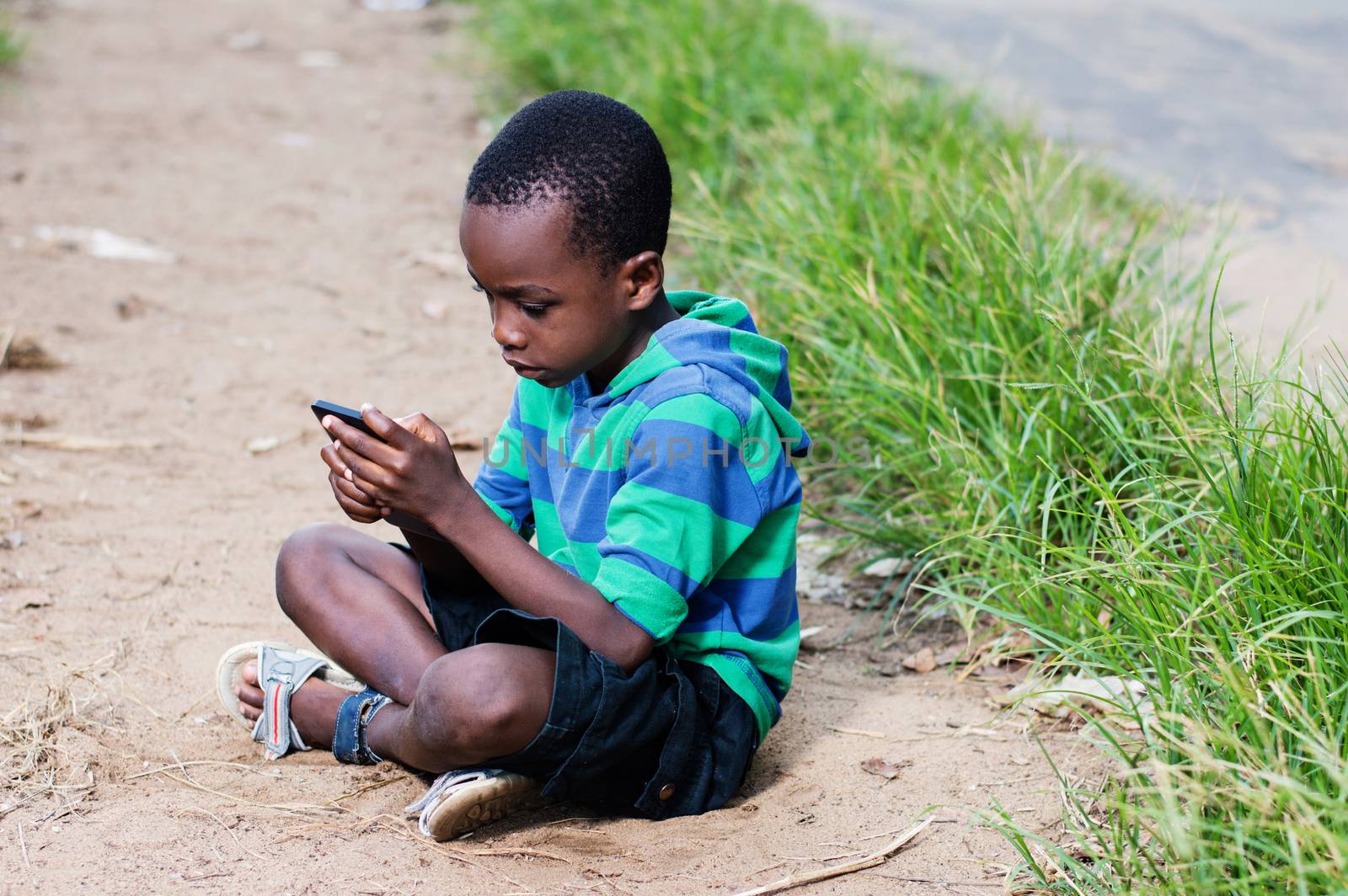 child sitting on the floor making games in a mobile phone in hand.