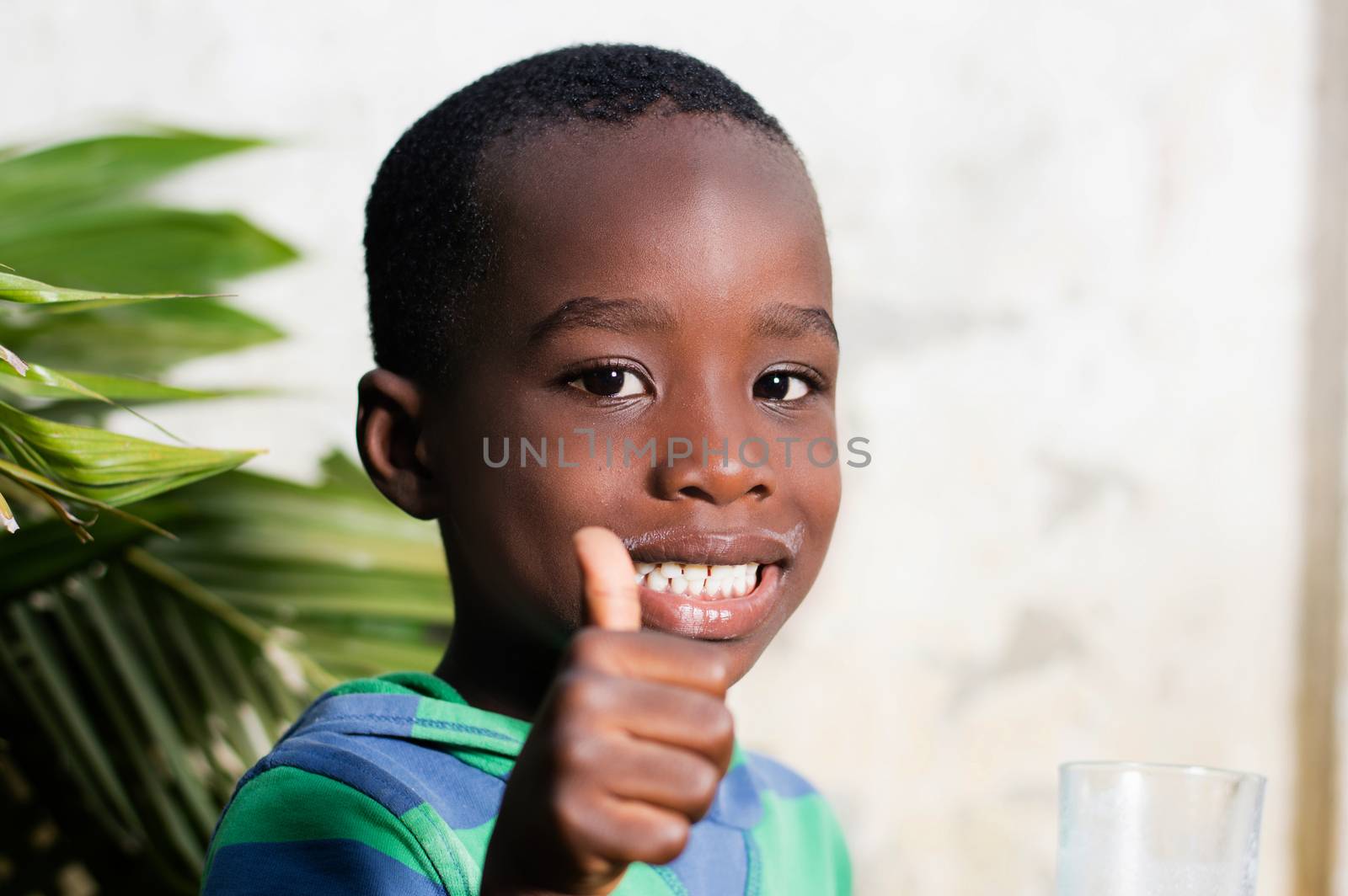 Happy child in a sign of appreciation after drinking a glass of milk.