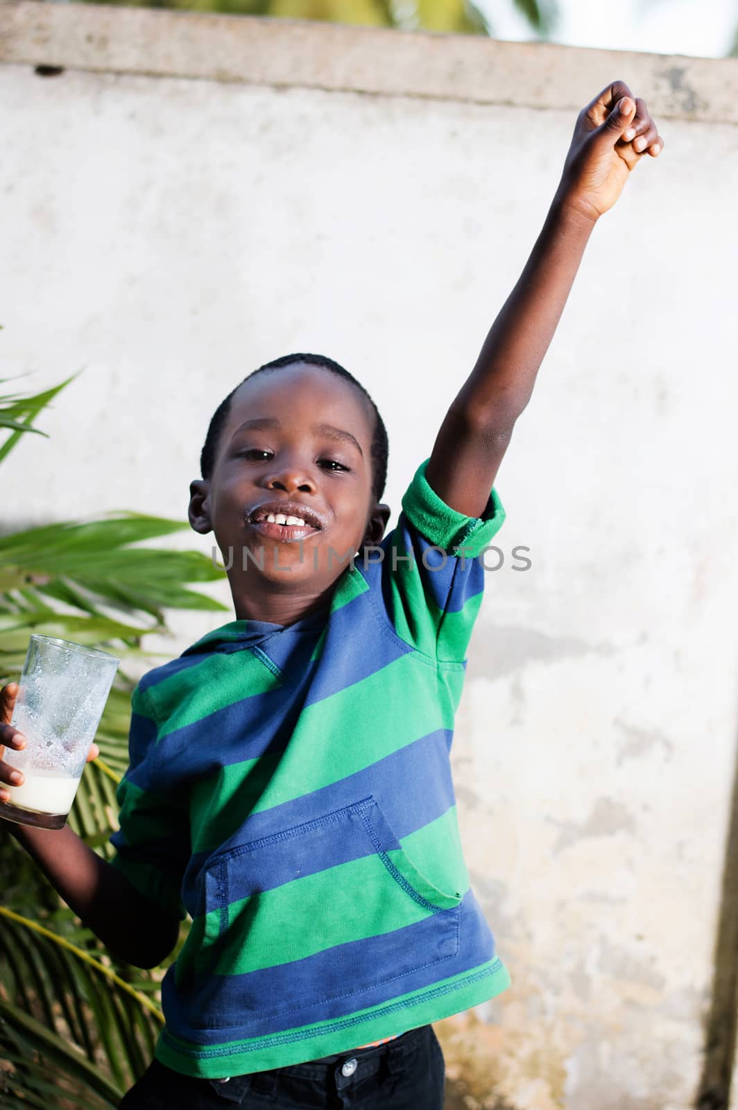 happy child holding a glass of milk manifested his joy, raising his arms.