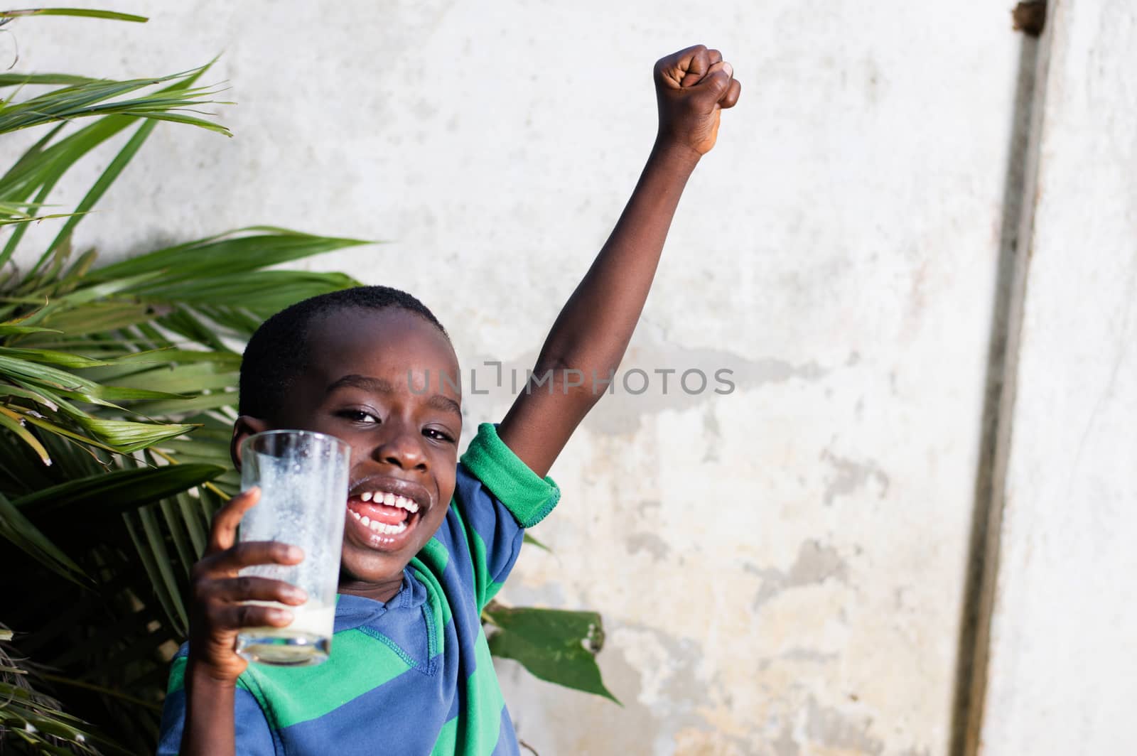 happy child holding a glass of milk manifested his joy, raising his arms.
