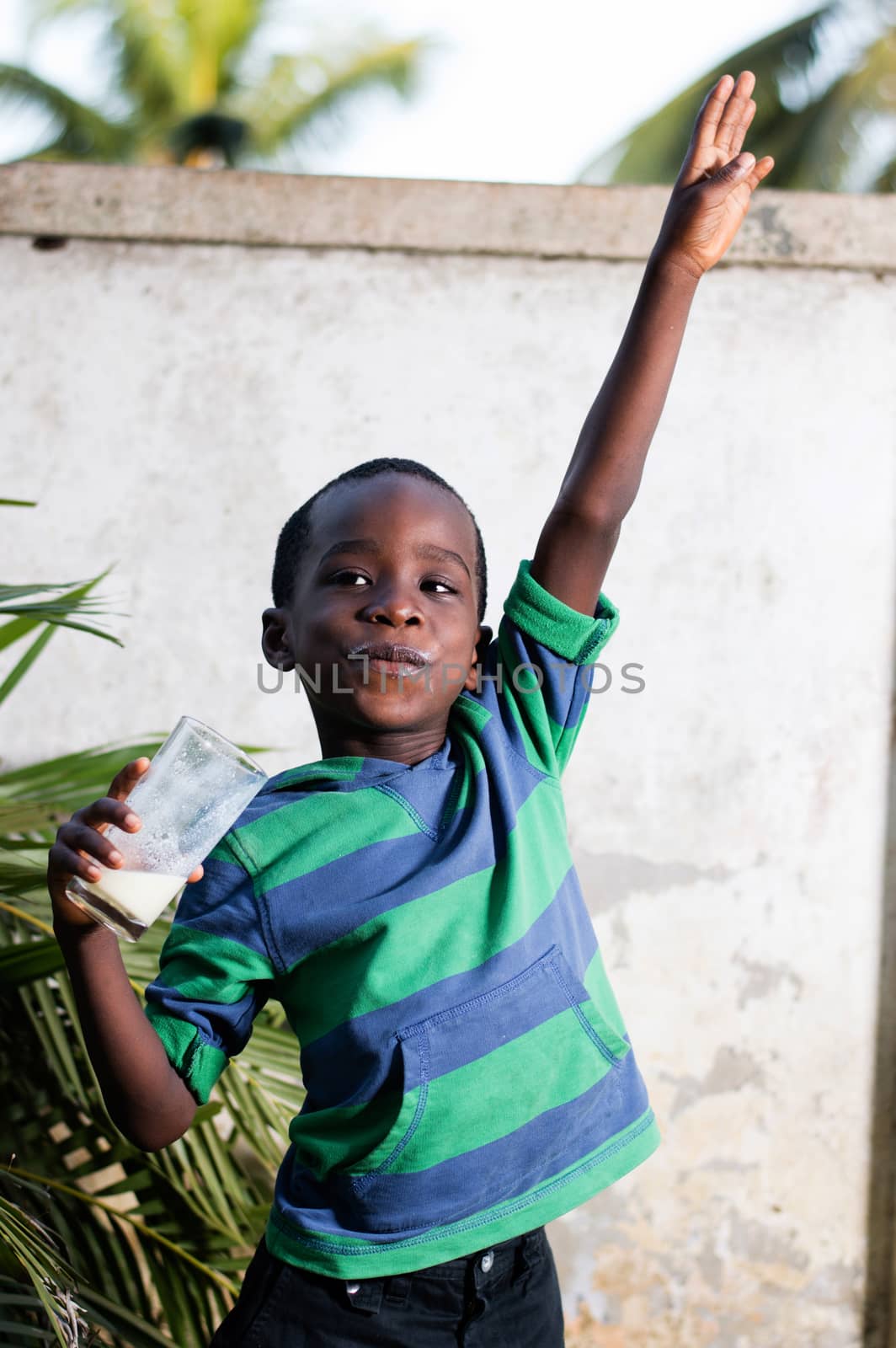 happy child holding a glass of milk manifested his joy, raising his arms.