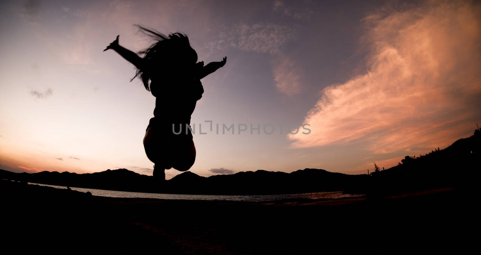 Silhouette, happy jumping Shadow girl Jump on the orange sky in the evening