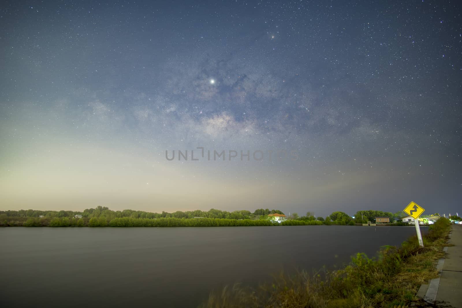 Signs, signs, beware of curves at night, behind the sign, with the Milky Way.	