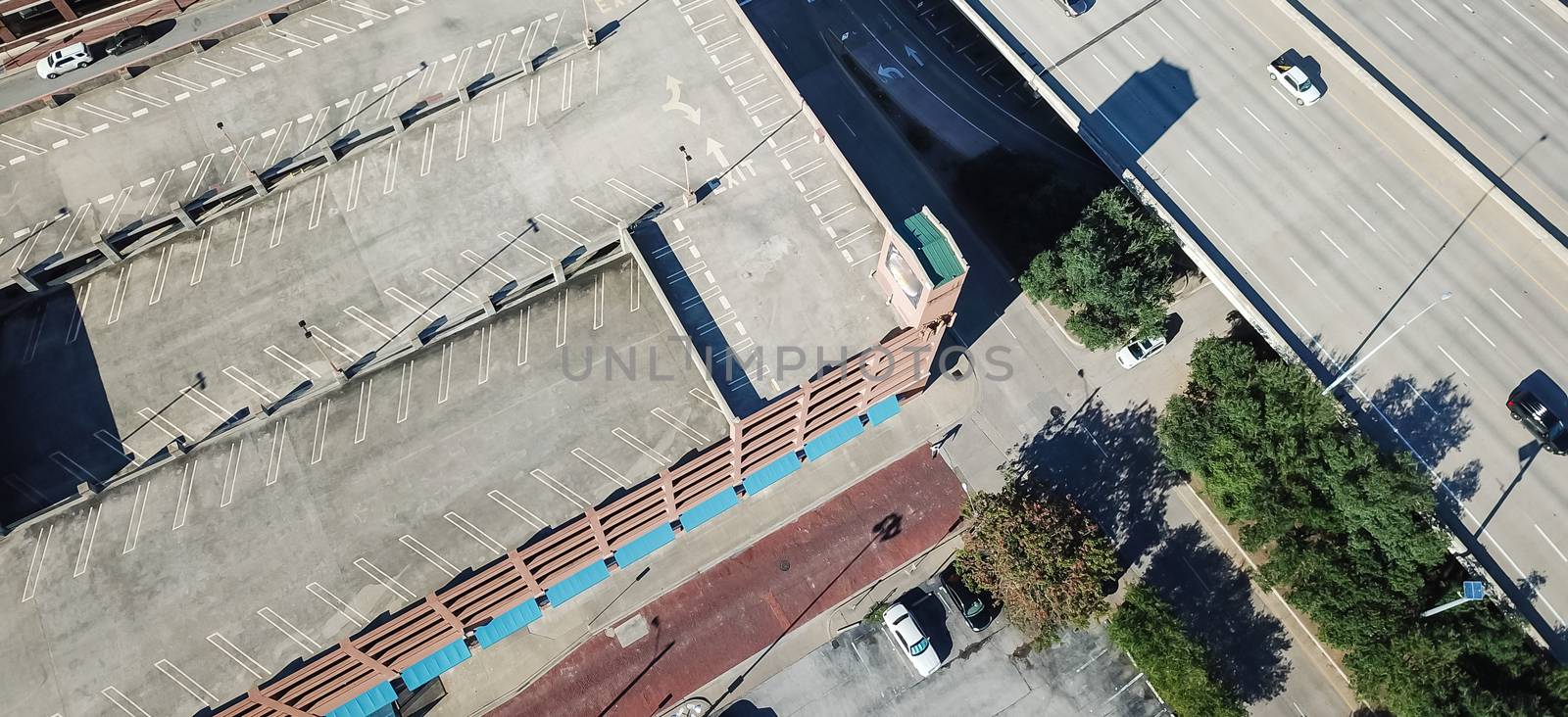 Panorama aerial view multistory car park and parking lots with many vacant spots in downtown Dallas, Texas. Top of rooftop parking infrastructure near highway