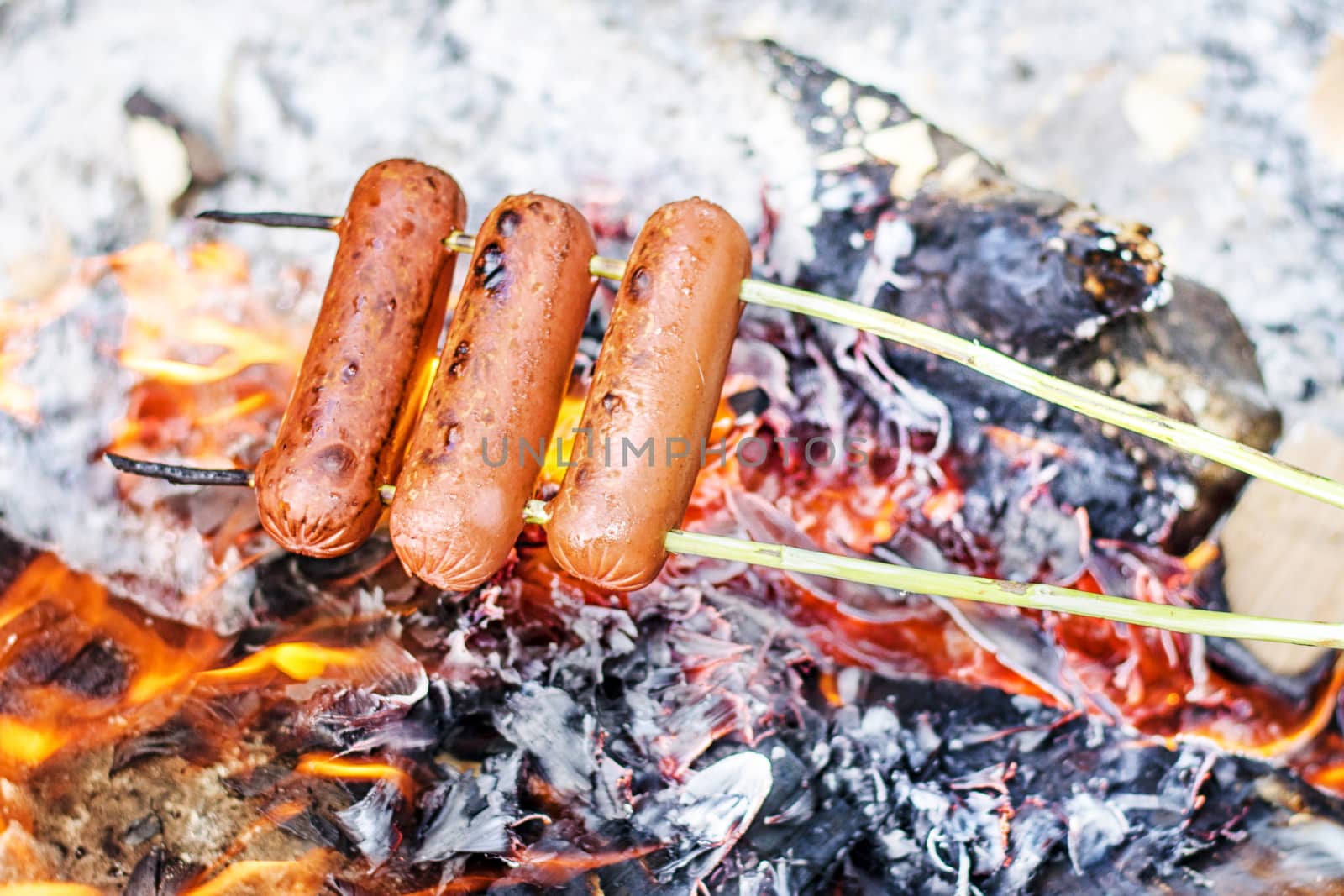 Grilling sausages over an open fire outdoors