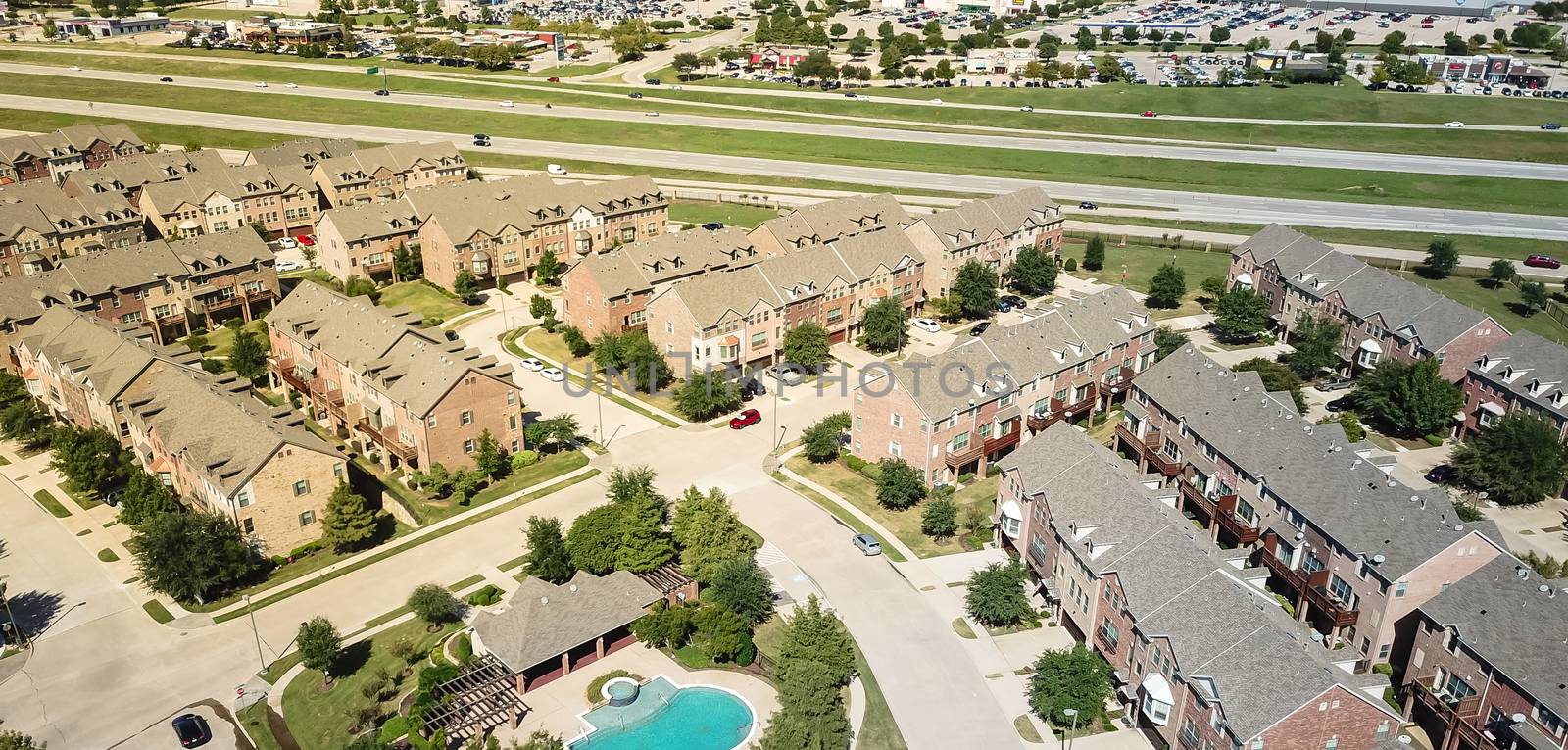 Panorama top view apartment complex near highway 635 and strip mall, marketplace suburban Dallas, Texas. Multistory rental building with swimming pool and attached garages