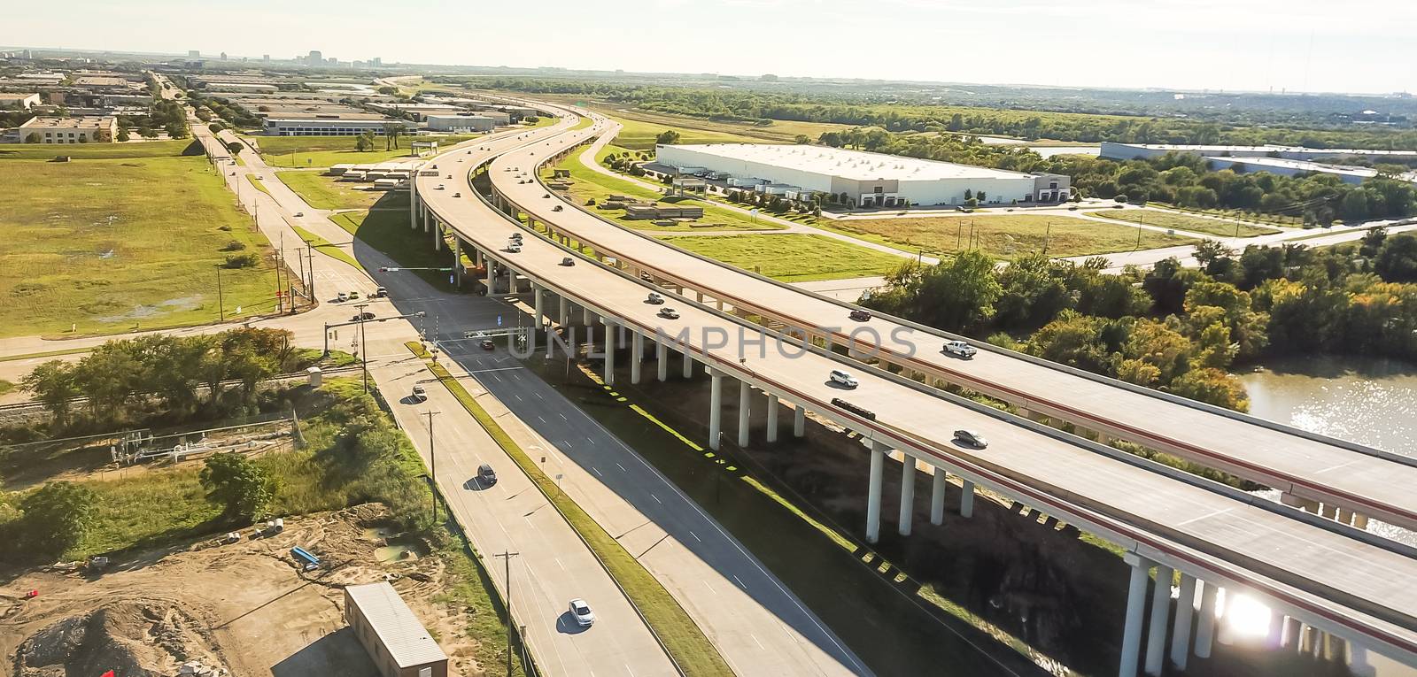 Panorama view flyover the elevated highway viaduct through flood area near busy construction site in Dallas, Texas, USA. Top of multilevel expressway near a lake, pillars under water