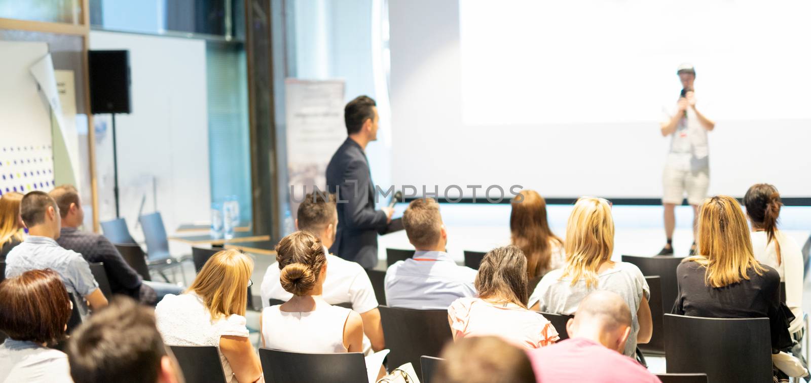 Businessman in audience standing and asking question to speeker at business conference. by kasto