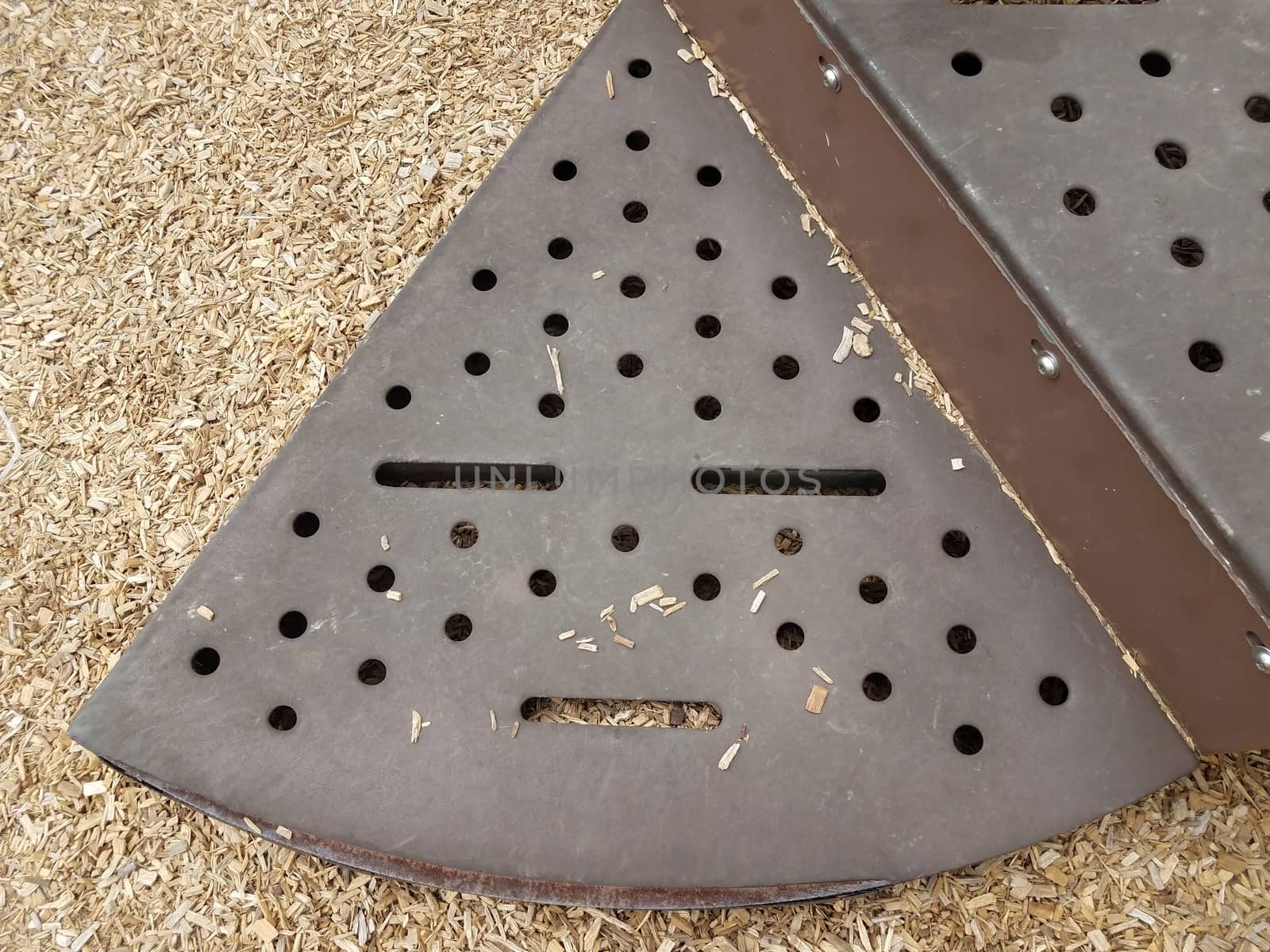 brown metal step on play stucture with holes that looks like a face