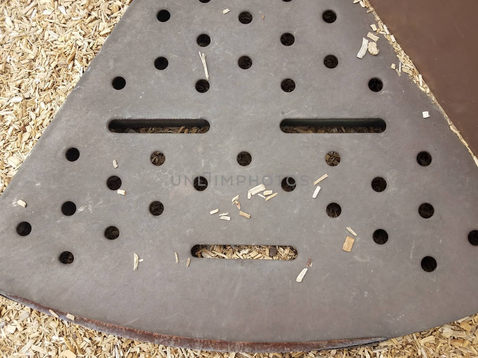 brown metal step on play stucture with holes that looks like a face