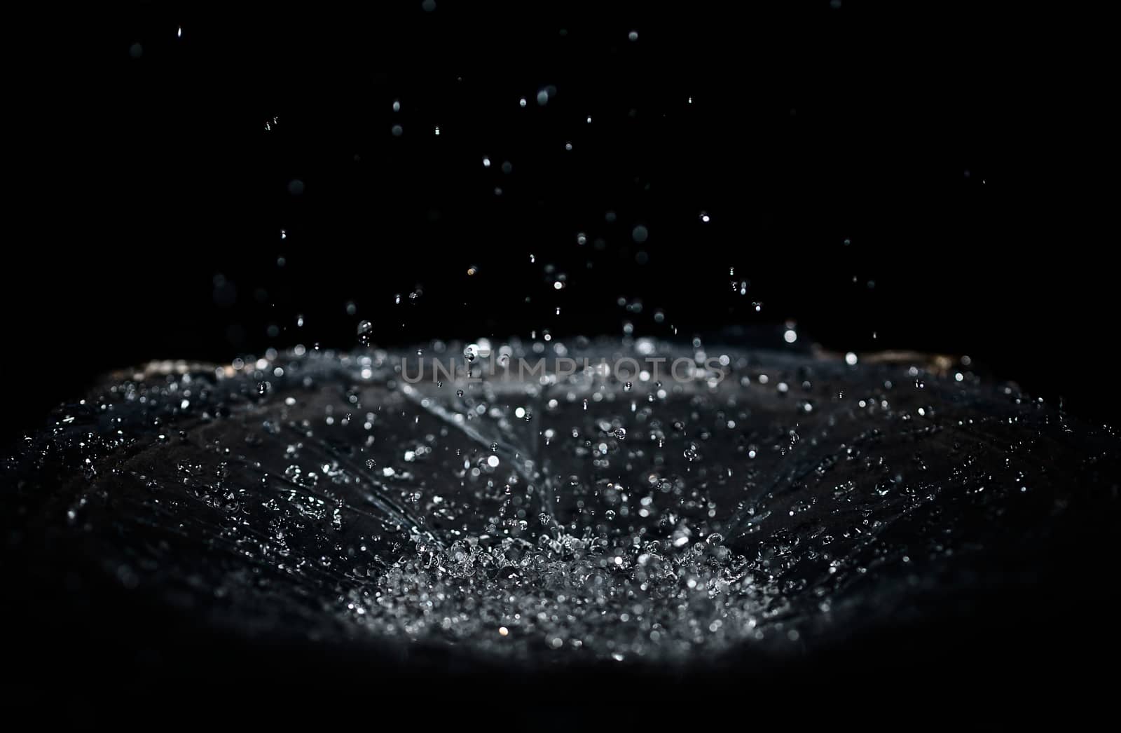 The splash of water drops in loudspeaker on black background. Pe by alexsdriver