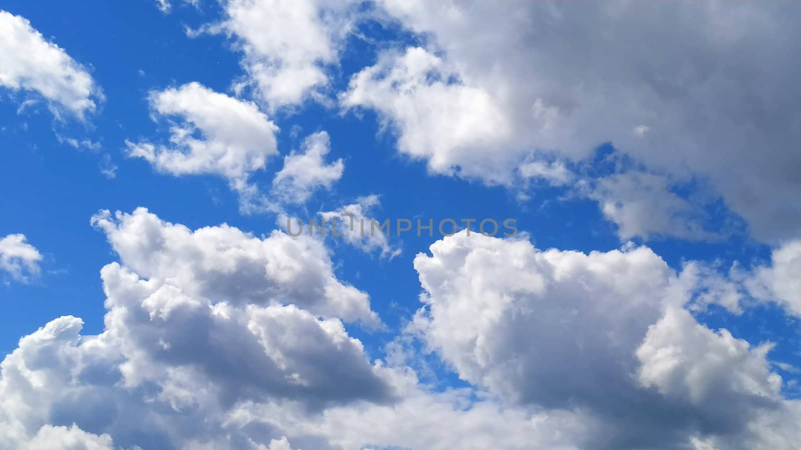 White cumulus clouds against a blue sky.