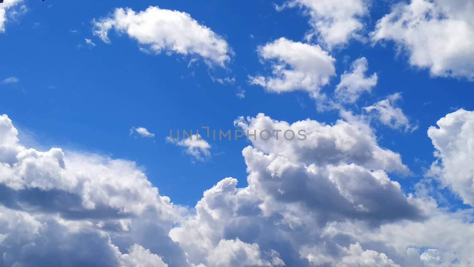 White cumulus clouds against a blue sky.