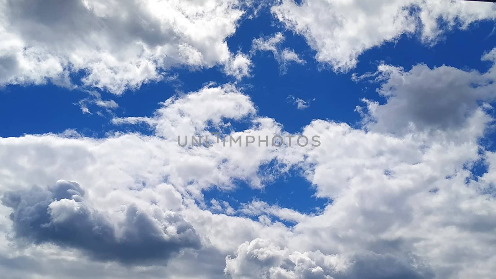 White cumulus clouds against a blue sky.