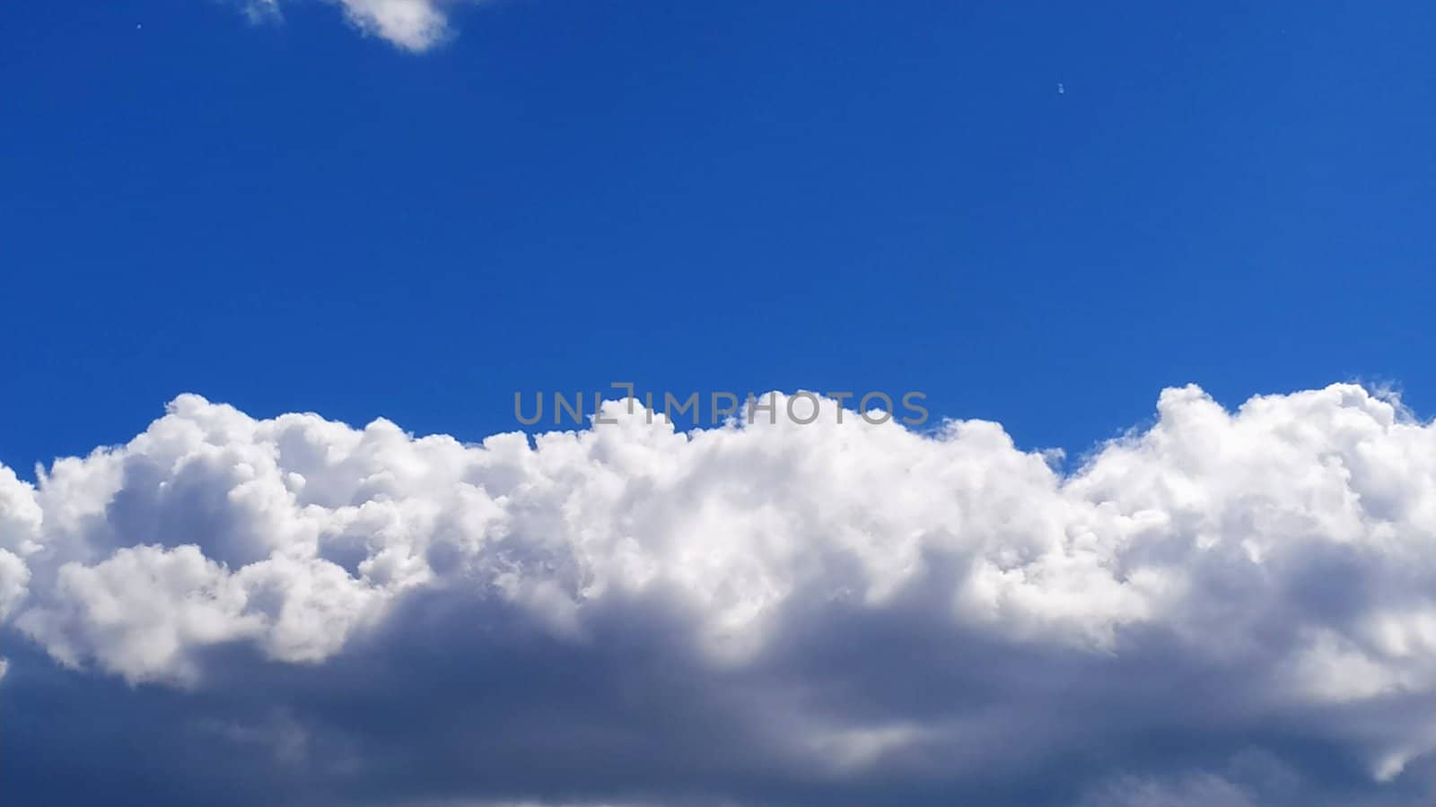 White cumulus clouds against a blue sky.