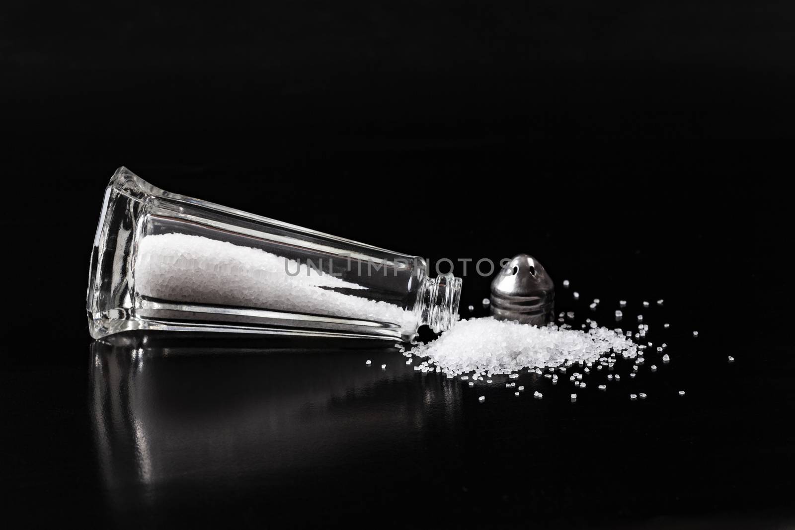 White Salt Pile With Shaker on Black Background with reflection