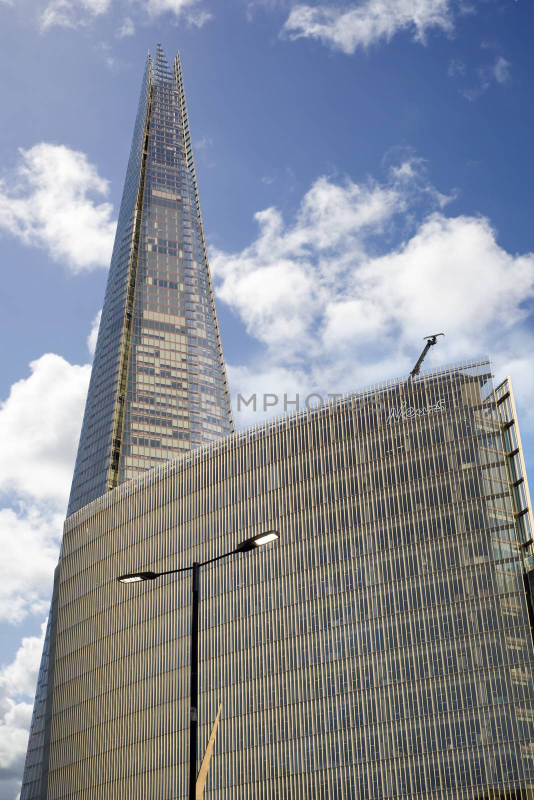 shard skyscraper towering over an office block by morrbyte