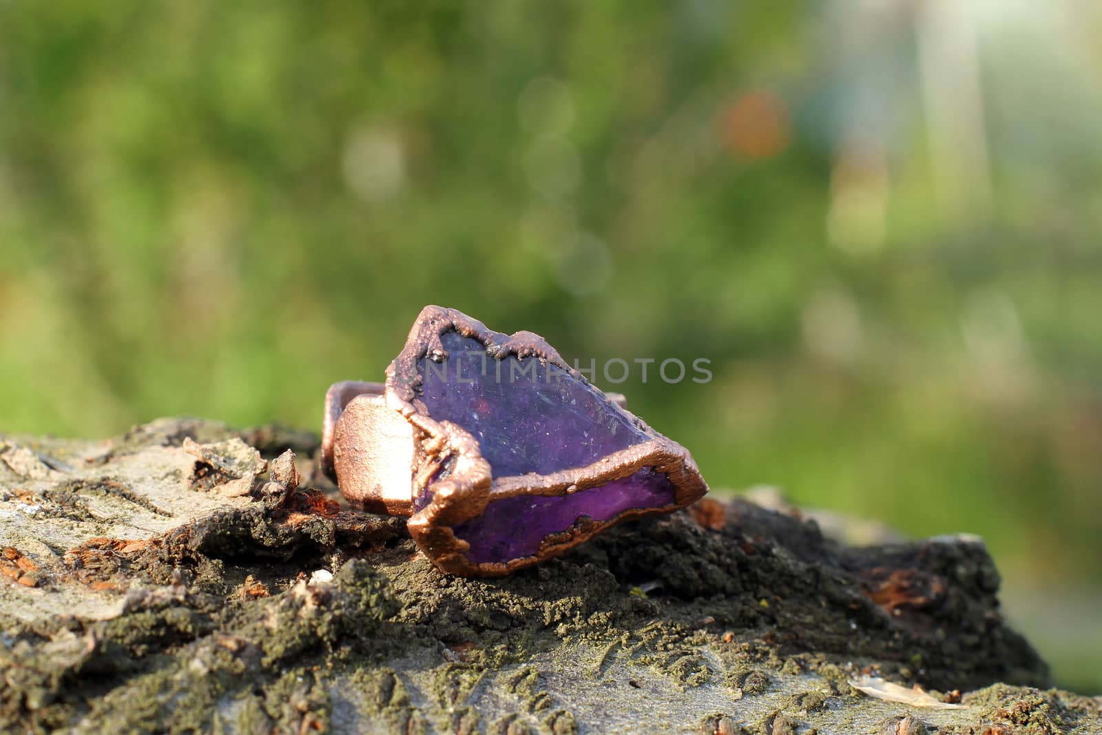 the Hand made copper ring with violet semiprecious stone on the wooden background