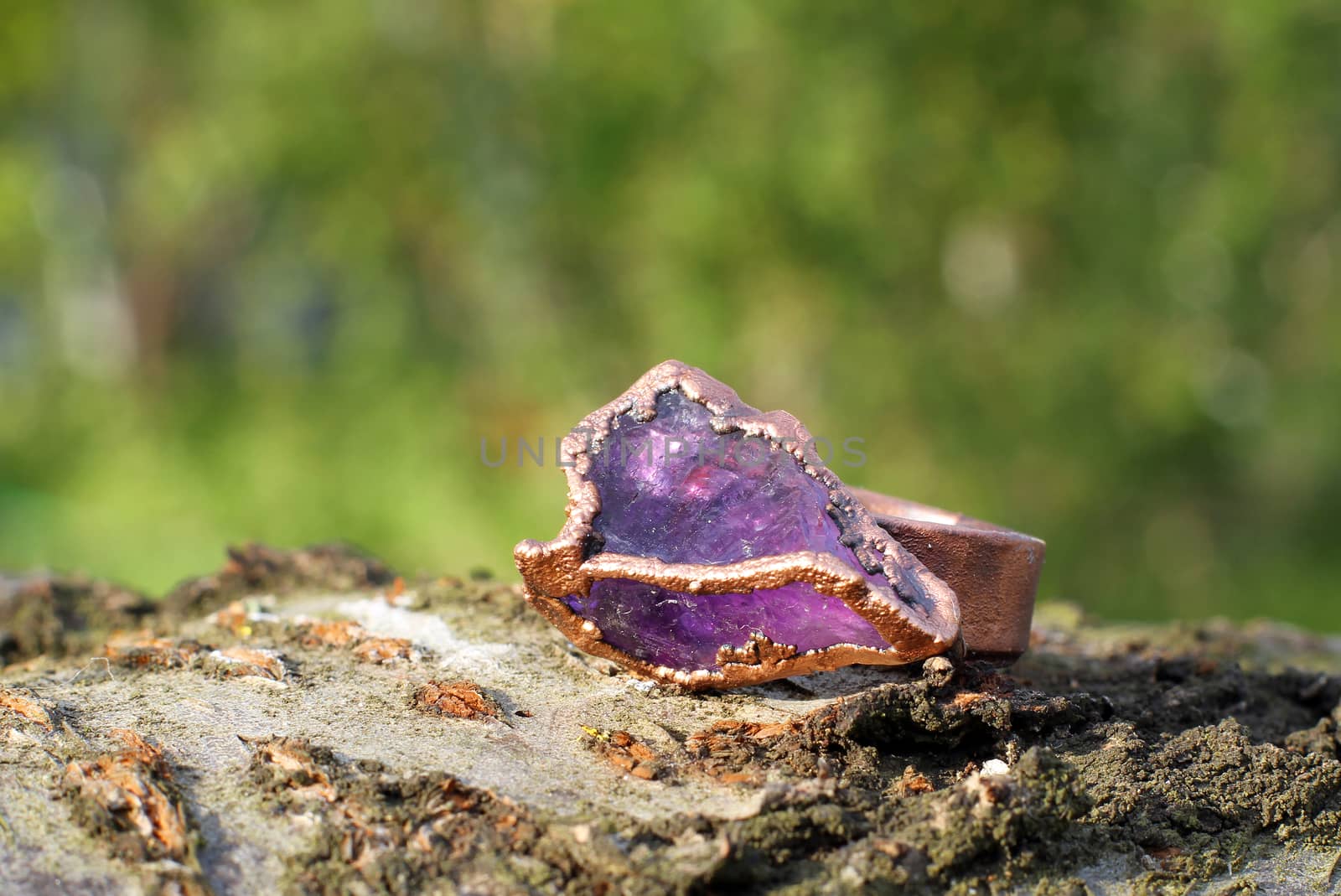 a Hand made copper ring with violet semiprecious stone on the wooden background
